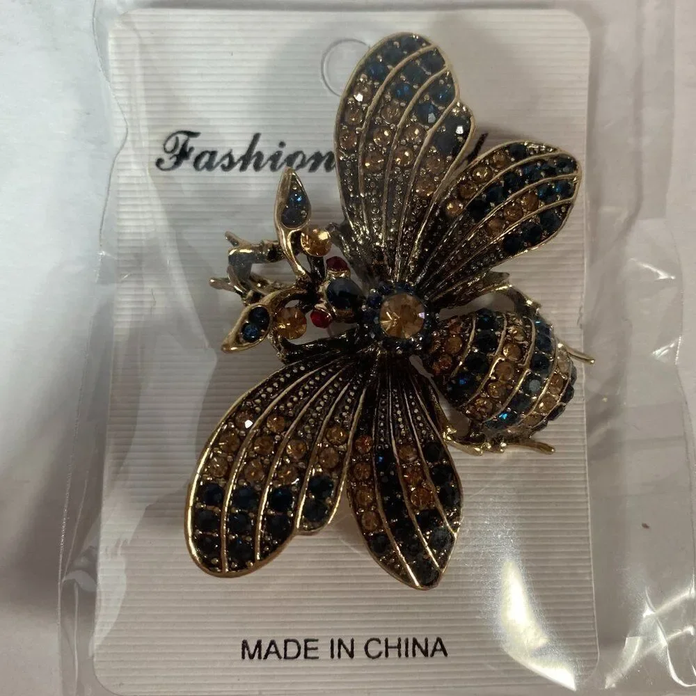 Rhinestone bee brooch pin with black and amber crystals, set in gold tone metal.